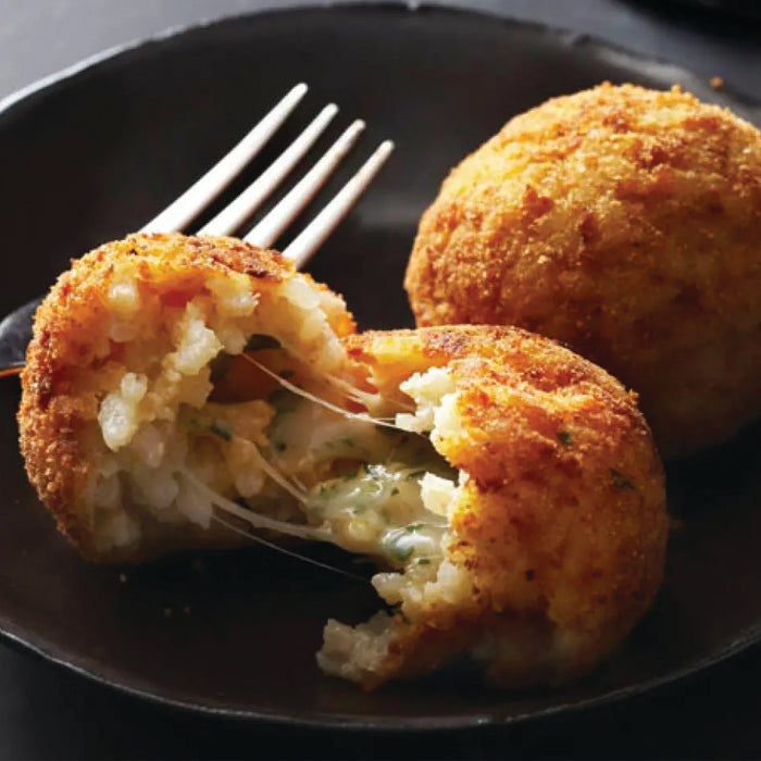 Cheesy breaded dish with a bite taken out on a black plate with a fork.