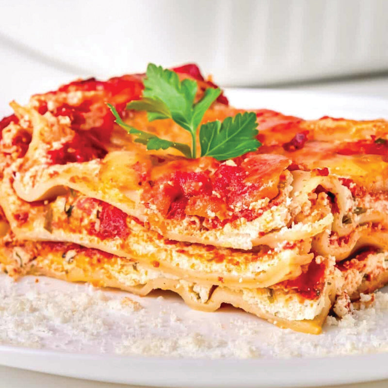 vegan Slice of lasagna on a white plate with a sprig of parsley