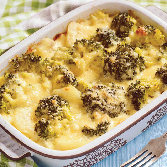Cheesy vegetable casserole with broccoli in a white dish on a green checkered tablecloth.