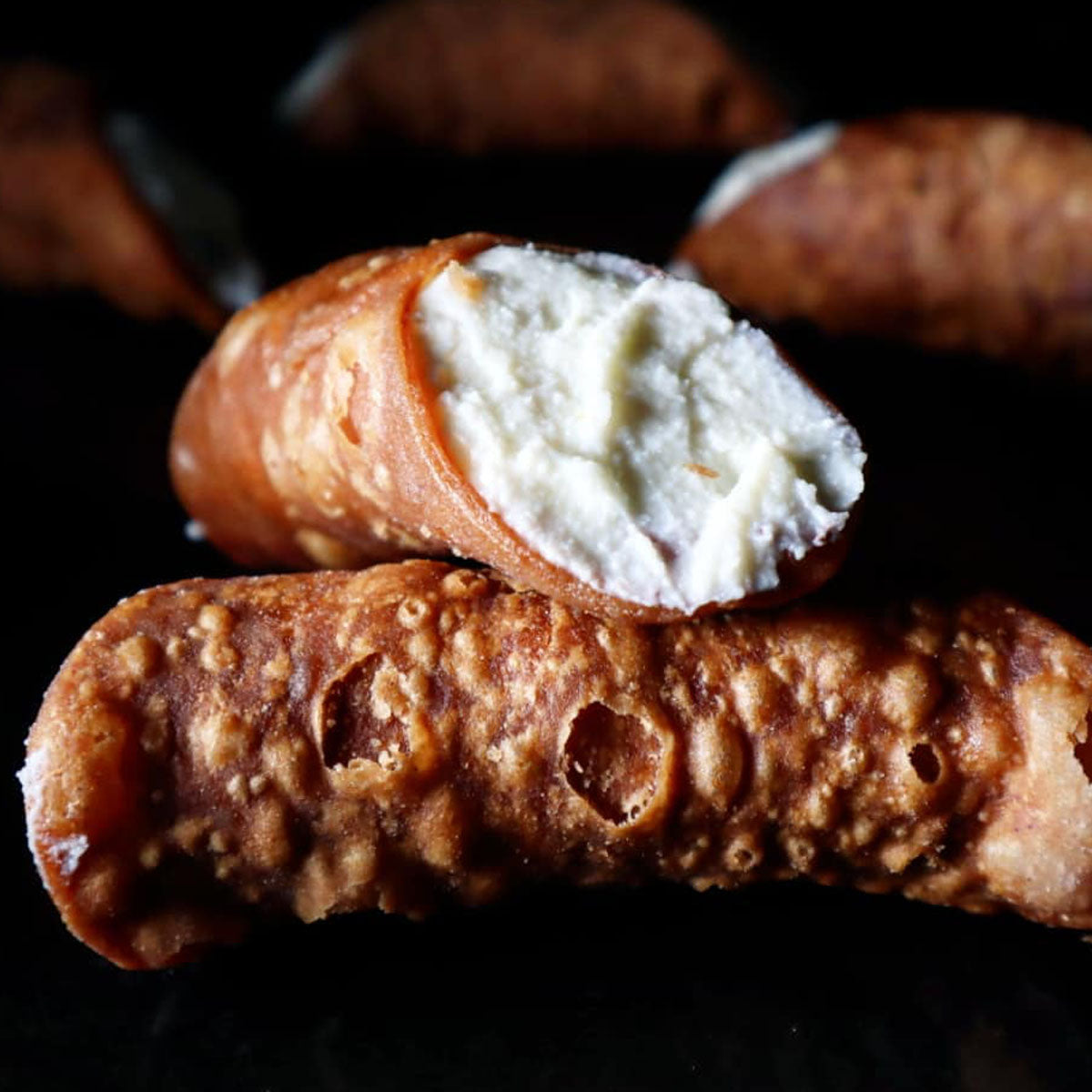 Close-up of a cannolo with ricotta filling on a dark background