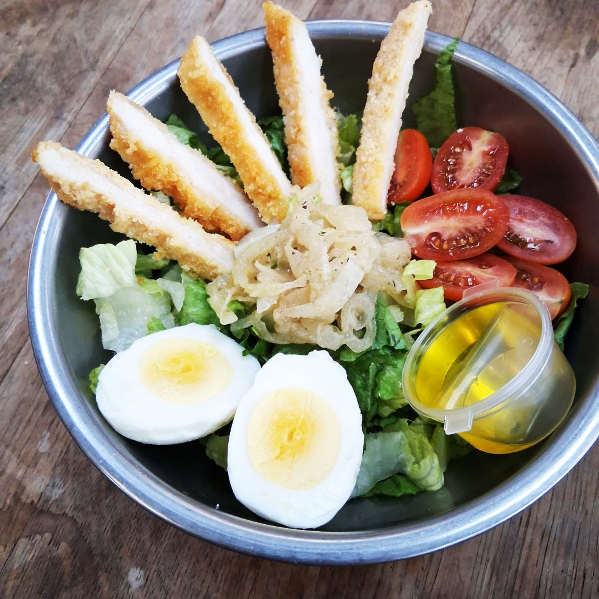 Italian Catering Salad with chicken strips, eggs, and tomatoes in a metal bowl on a wooden surface