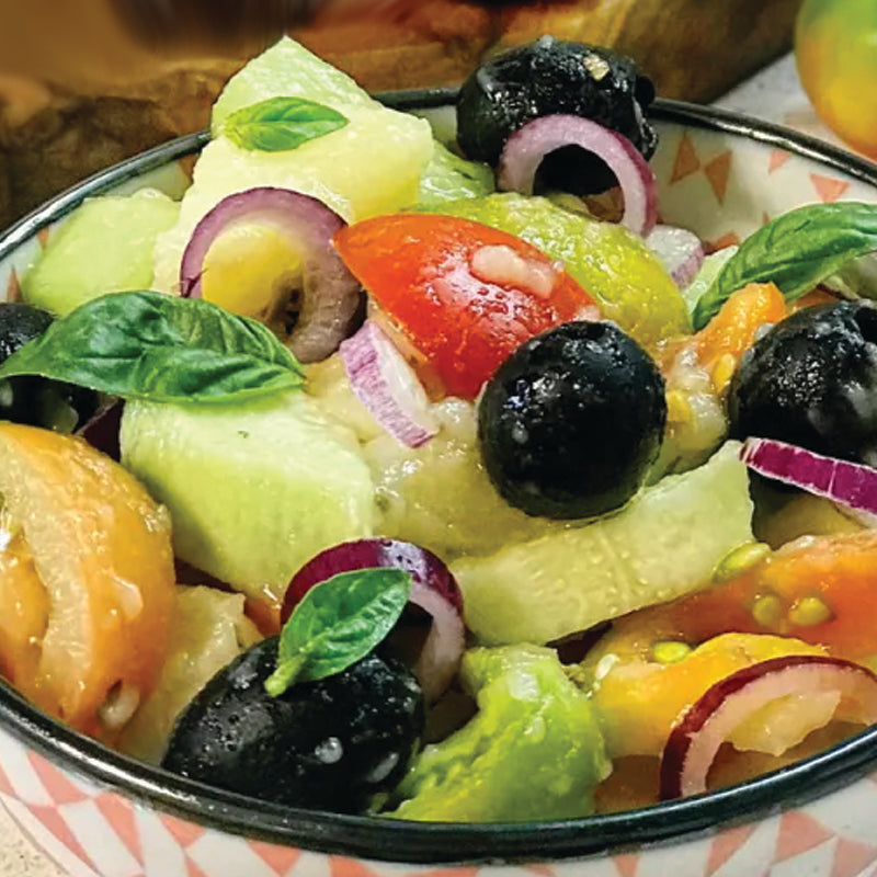 Italian catering Cialda Barese  salad with cucumbers, tomatoes, olives, and other vegetables in a bowl.