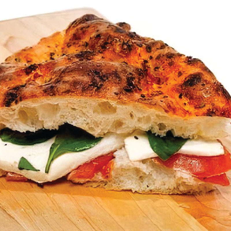 Italian Catering Caprese focaccia with mozzarella, tomatoes, and basil on a wooden board