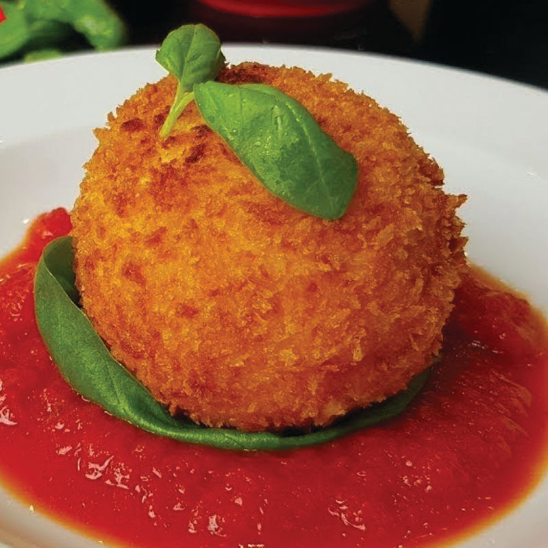 Crispy fried burrata dish on a bed of red sauce with basil leaves