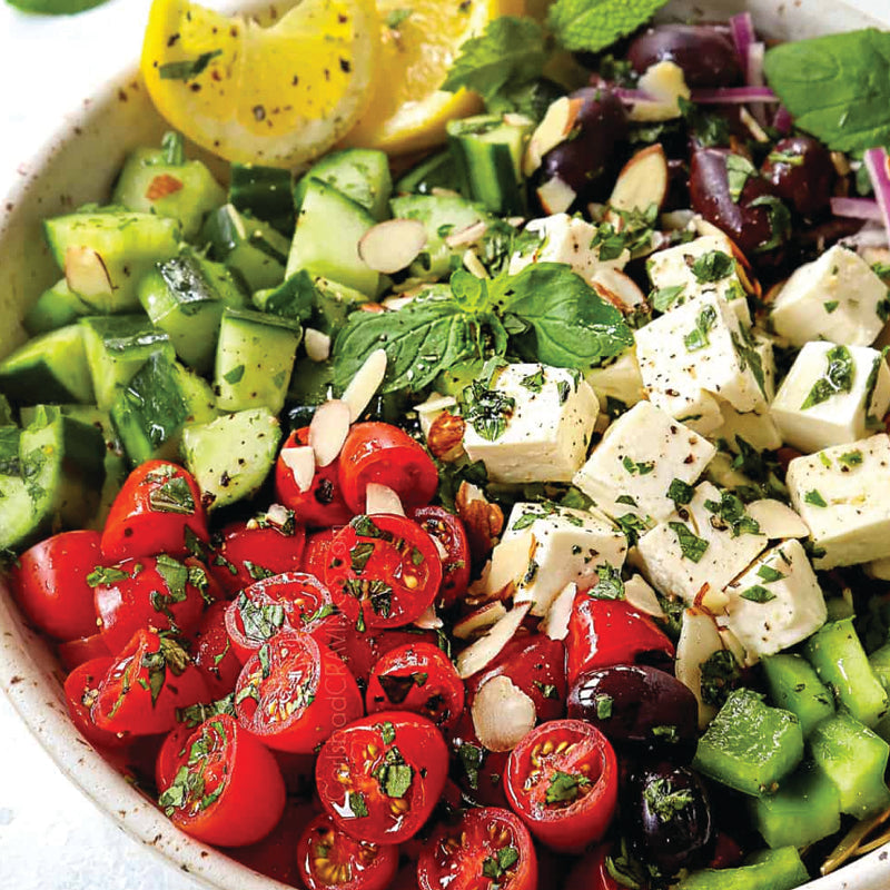 Italian Catering mediterranean salad with cucumbers, tomatoes, feta cheese, and herbs in a bowl.