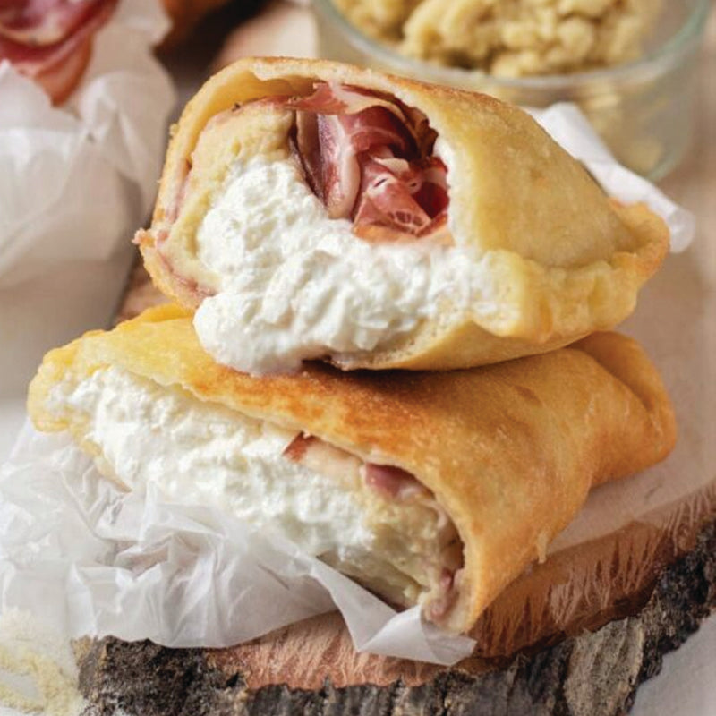 panzerotto fried pizza showcasing creamy burrata at its heart, surrounded by paper-thin Parma prosciutto, vibrant arugula pesto, and a dusting of cracked black pepper and parmesan