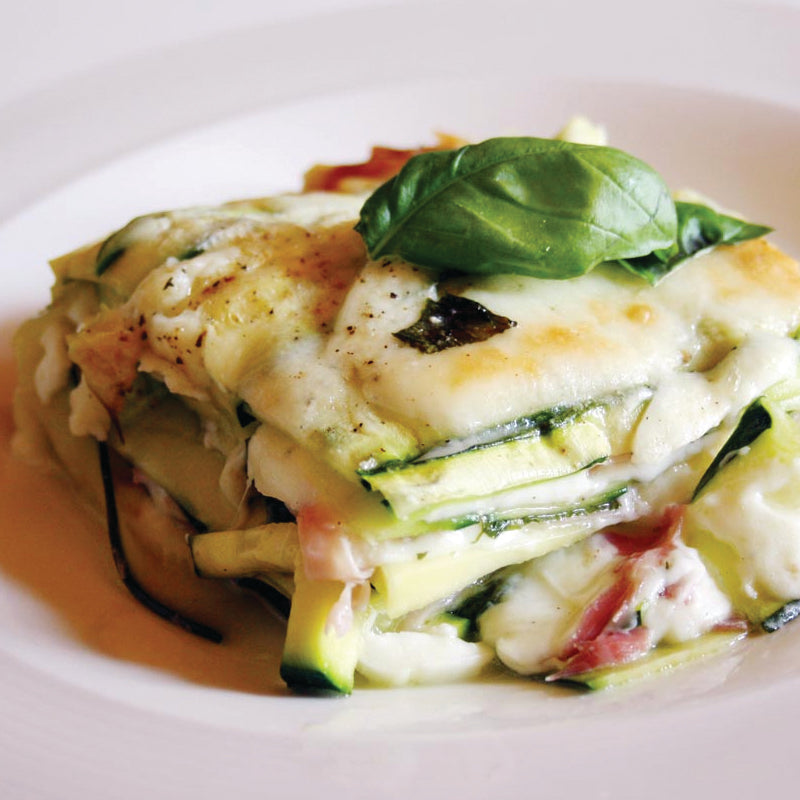 Zucchini lasagna on a white plate with a basil leaf
