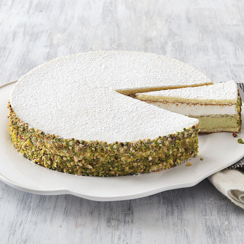 Pistachio cake with a slice removed on a white plate