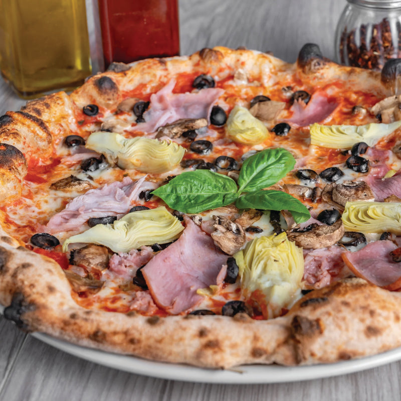 Capricciosa pizza captures the essence of Italian tradition with tomato sauce, mozzarella, kalamata olives, sautéed mushrooms, artichoke, and ham.