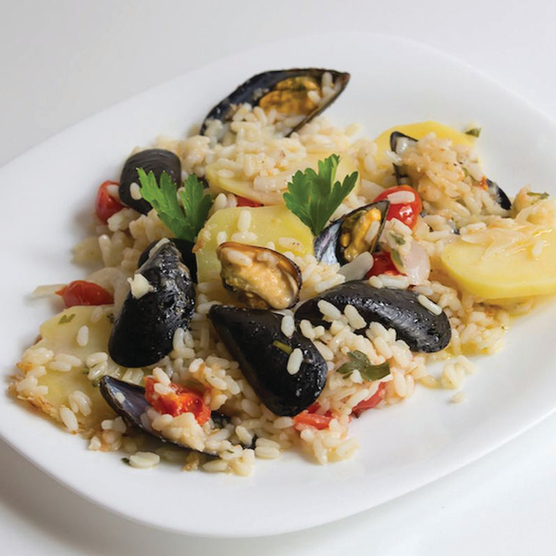 Risotto with mussels and vegetables on a white plate