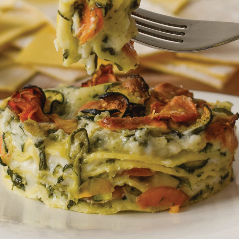Vegetable lasagna being lifted with a fork on a white plate