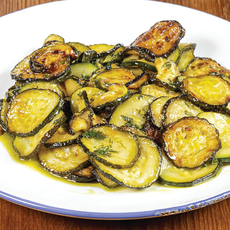 Sliced zucchini with a glossy sauce on a white plate